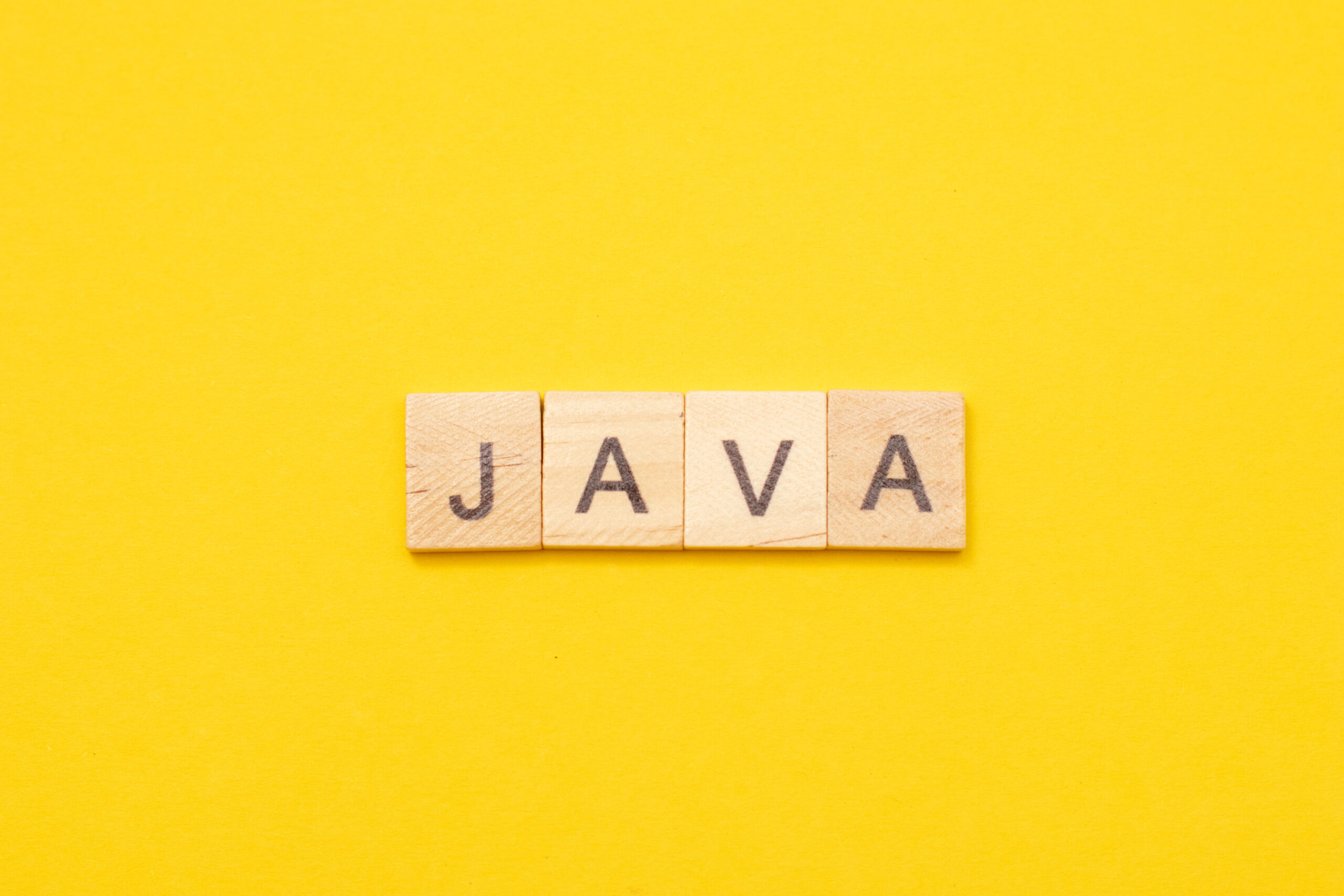 Word JAVA made from wooden letters on yellow background